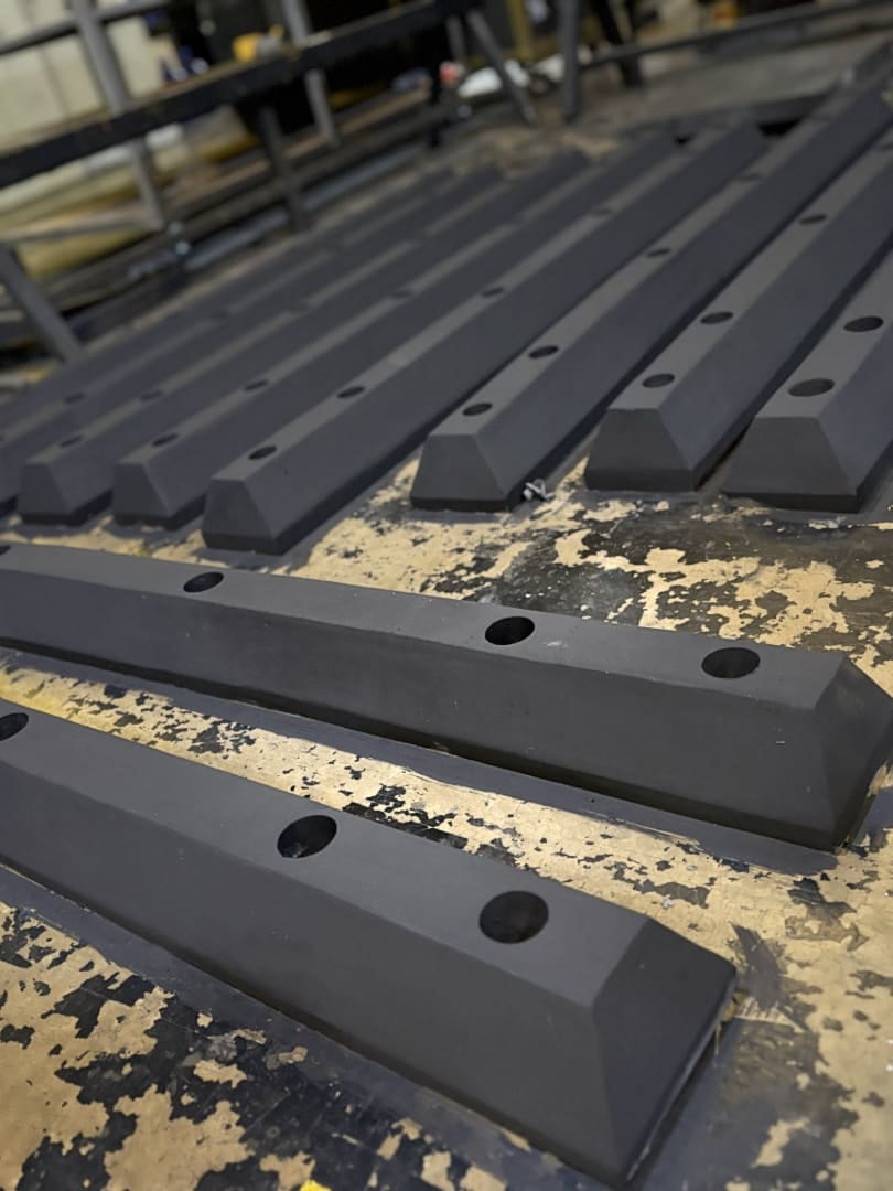Heavy-duty black rubber loading dock bumper mounted on a warehouse dock face