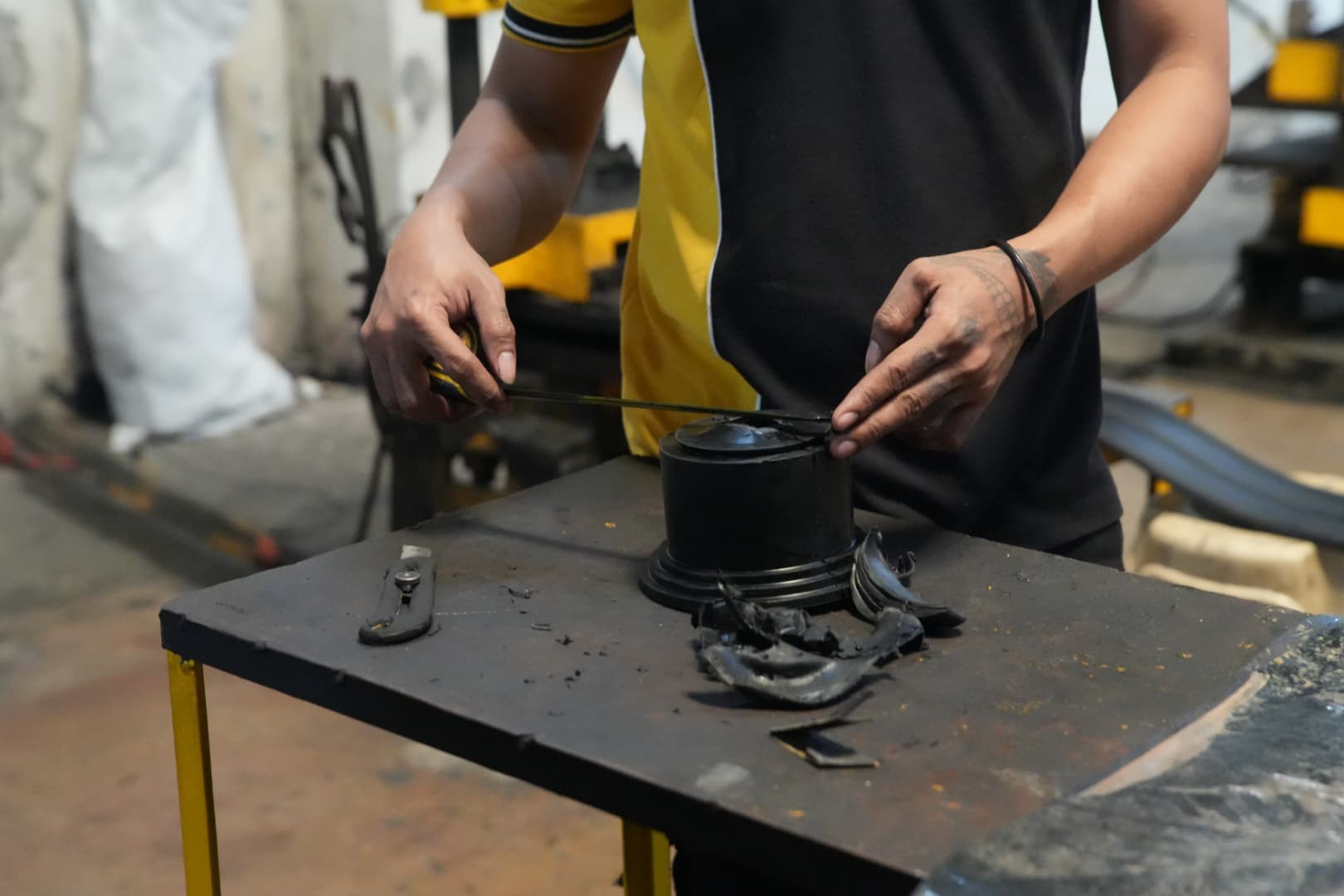 Worker trimming flash from a freshly molded rubber coupling element with a knife